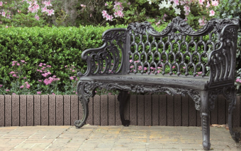 wrought iron bench with a flower garden background